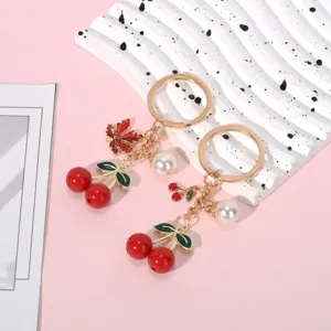 Close-up of vibrant red resin cherry keychains featuring elegant pearls and maple leaf charms