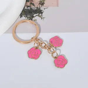 Close-up detail of a gold keychain featuring three beautiful pink enamel rose pendants