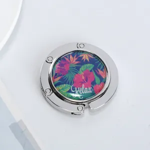 Close-up of a foldable purse hook with a tropical floral pattern and Relax text