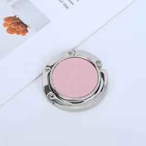 Close-up view of a portable circular desk bag hook with elegant pink faux leather inlay.