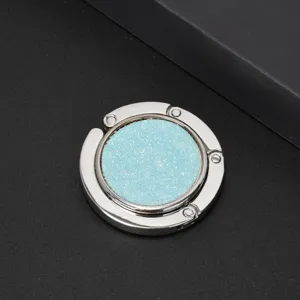 Close-up of portable silver folding bag hook with sparkling blue glitter inlay