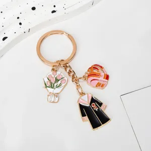 Detail view of gold graduation keychain with bachelor gown, school bag and tulip charms.