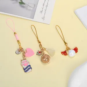 Close-up of cute alloy phone straps featuring cat paw, tassel, and pearl charms