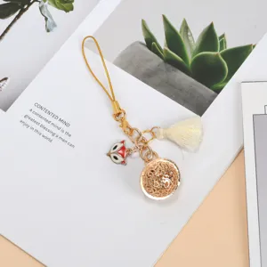 Detail of golden alloy fox charm phone strap with elegant cream tassel and carved ball