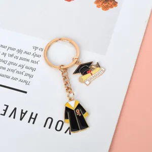 Detalle del llavero dorado con colgantes de toga y birrete de graduación académico.