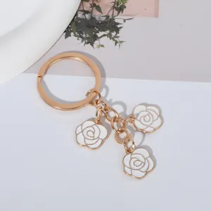 Detail shot of white enamel roses on a minimalist golden craft keychain pendant