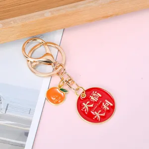 Close-up detail of metal keychain featuring orange charm and Good Luck slogan pendant