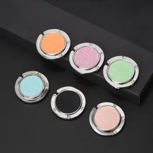 Detailed view of six colorful glitter circular folding portable metal handbag table hooks