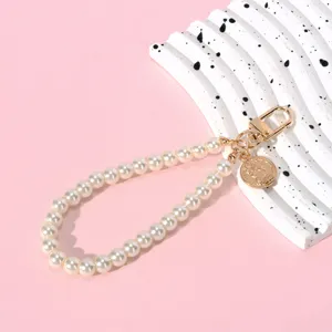 Close-up of elegant pearl chain with golden coin pendant and lobster clasp detail