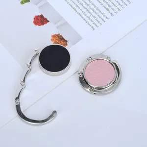 Detail view of foldable portable purse hooks in black and pink leather for desk edges