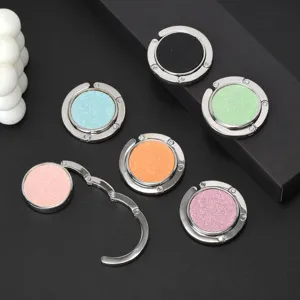 Macro view of six colorful folding handbag hooks with glittery pastel finishes on black background