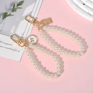 Elegant pearl chain charms with gold lobster clasps and vintage-style pendant details.
