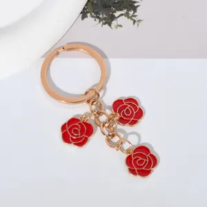 Elegant gold-tone keychain featuring three vibrant red enamel rose charms for gifts.