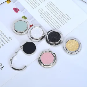 Set of six colorful foldable purse hooks for desks with various textured finishes.