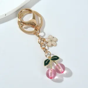 Close-up detail of translucent pink cherry and white flower charms on a gold keychain