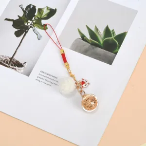 Close-up of a cute fox charm with a white pompom on a stylish red cord phone strap