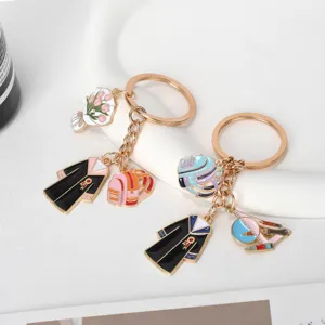Detailed view of graduation gown keychains with colorful enamel charms on stand.
