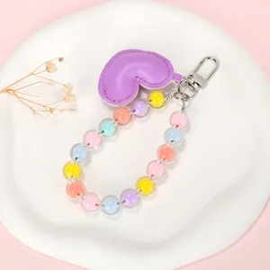 Detailweergave van kralenketting in macaronkleuren met paarse hartvormige sleutelhanger