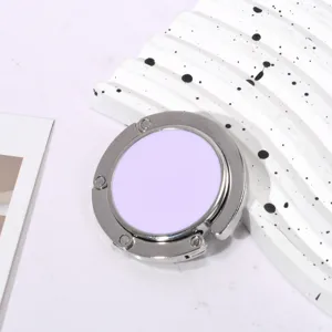 Detailopname van een lila opvouwbare tassenhaak op een witte getextureerde ondergrond.