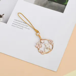 Close-up of a cute alloy cat and cherry blossom charm with a golden cord
