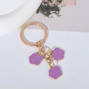 Detailed view of the purple enamel triple rose flower charms on the golden keychain