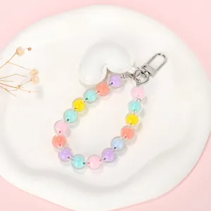 Detail van de telefoonarmband met macaronkleurige kralen en een witte hartjes hanger