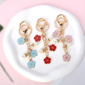 Detalle de los llaveros de esmalte de flor de cerezo rosa, azul y rojo con perlas finas.