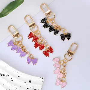 Detailed view of colorful enamel bow keychains in purple, red, black, and pink colors