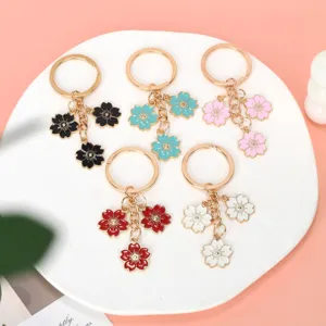 Various colorful enamel cherry blossom keychains displayed on a white ceramic plate
