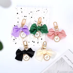 Detail of colorful satin bow keychains with gold pendants on a minimalist background
