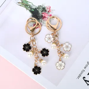 Detalle de llaveros de metal con flores de cerezo, esmalte y perlas blancas
