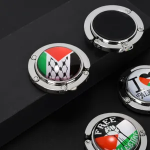 Close-up of foldable purse hooks featuring Palestine flag designs on black background.
