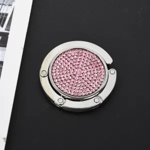 Nahaufnahme eines kreisförmigen faltbaren Metall-Taschenhalters mit rosa Strasssteinen