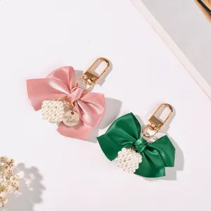 Detailed view of elegant pink and green satin ribbon bow keychains with white pearl cube charms
