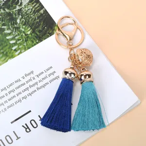 Detailed view of gold bell and vibrant blue silk tassels on a stylish gift keychain.