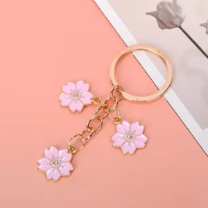 Close-up detail of three pink enamel cherry blossom charms on a gold-tone keychain