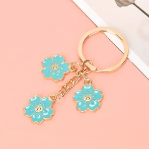 Close-up of three turquoise cherry blossom pendants on a golden metal keychain