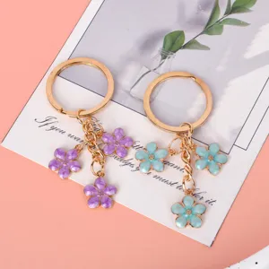 Detail of gold metal keychains with purple and mint enameled cherry blossom charms