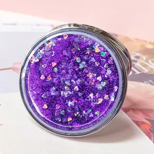 Close-up of a portable round quicksand makeup mirror with purple heart-shaped glitter