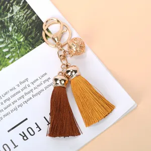 Detailed view of handmade double tassel keychain with golden bell and lobster clasp