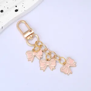 Detailed view of three pink enamel bow charms on a gold-plated lobster clasp keychain