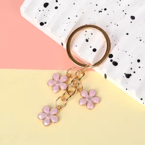 Detailed close-up of delicate pink enamel cherry blossom charms on a gold-tone metal keychain