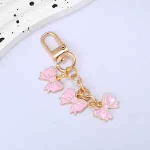 Detailed view of a gold-tone keychain featuring three adorable pink enamel bows
