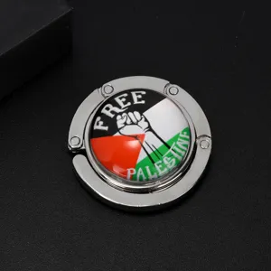 Close-up detail of a foldable metal table bag hook with a Free Palestine flag motif