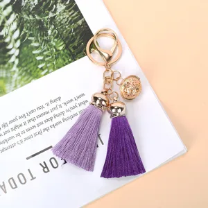 Detailed view of gold keychain with purple tassels and hollow sphere bell.