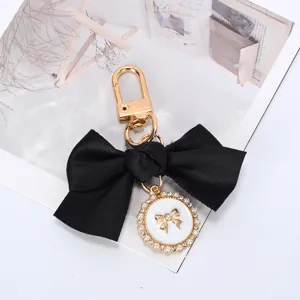 Close-up of black ribbon bow keychain with elegant pearl charm and gold-tone clip.