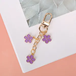 Macro detail of a purple enamel flower keychain with gold alloy chain and lobster clasp