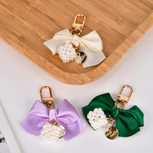 Close-up view of colorful satin bow keyrings featuring a pearl cube and gold charms