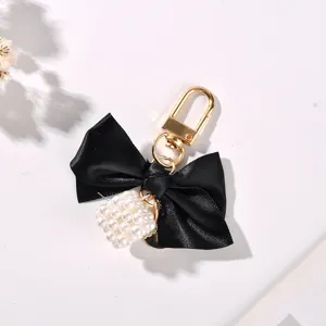 Close-up view of black ribbon bow keychain with an elegant pearl cube charm detail