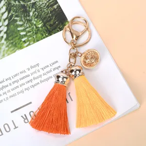 Macro detail of vibrant orange and yellow silk tassel keychain with decorative gold bell